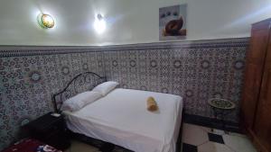 Dormitorio pequeño con cama blanca en la pared en Dar Ahl Tadla, en Fez