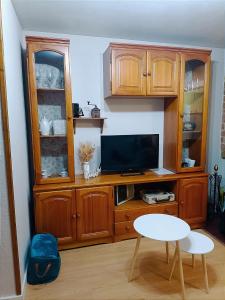 cocina con armarios de madera, mesa y TV en Mirador de Bergosa, en Castiello de Jaca