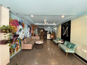 een woonkamer met een bank en een schilderij aan de muur bij Armoni Patong Beach Hotel in Patong Beach