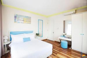 een witte slaapkamer met een bed en een bureau bij Cọ Xanh Hotel in Da Nang