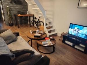 ein Wohnzimmer mit einer Couch und einem Tisch und einem Fernseher in der Unterkunft L'Oasis du Quesnoy - proche lille - Navette à disposition in Quesnoy-sur-Deûle