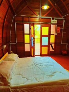 Cama grande en habitación con ventanas coloridas en LBA chalet, en Balik Pulau