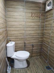 a bathroom with a toilet and a wooden wall at LBA chalet in Balik Pulau