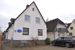 a white house with a black car parked in front at Haus Seehase Ferienwohnung Nr 03 in Haffkrug