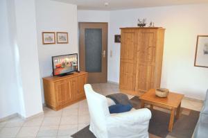 uma sala de estar com uma televisão, uma cadeira branca e uma mesa em Haus Windrose Ferienwohnung Nr 01 em Niendorf