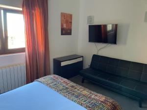 a bedroom with a bed and a couch and a television at Apartamentos Los Tojos in Colsa