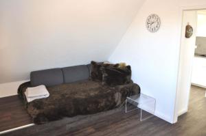 a couch in a living room with a clock on the wall at Landhaus Köppen Ferienwohnung Nr 15 in Timmendorfer Strand