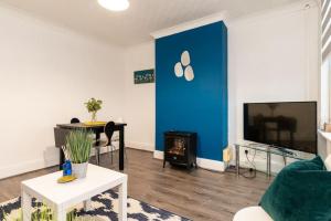 sala de estar con pared de acento azul y TV en Brand New Must See Stylish Apt W/Free Parking en Leicester