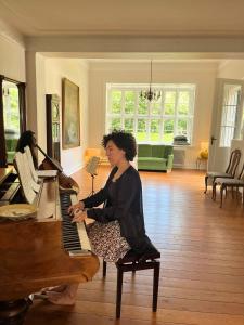 a woman sitting at a piano in a living room at Bellinge House in Horreby
