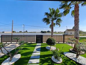 a garden with palm trees and a fence at La caseta del canal in Deltebre