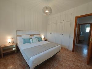 a bedroom with a large white bed with blue pillows at La caseta del canal in Deltebre +47 photos