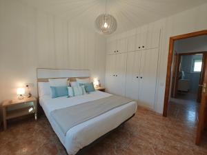 a bedroom with a large white bed with blue pillows at La caseta del canal in Deltebre