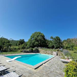 una piscina en un patio con sillas alrededor en Borgo il cantuccio - Casa Simona con piscina condivisa, en Molino di Renzetti