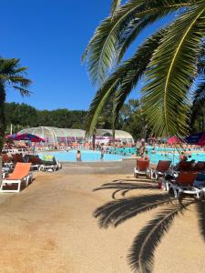 einen Pool mit Stühlen und Palmen am Strand in der Unterkunft Chez Vane et JP in Lège-Cap-Ferret