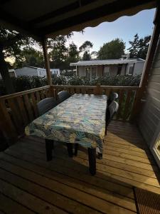 una terraza de madera con mesa y sillas. en Chez Vane et JP, en Lège-Cap-Ferret