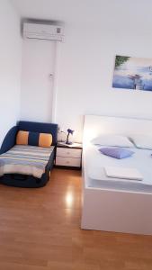 Habitación blanca con cama y sofá en Apartmani Roza Lopar, en Lopar