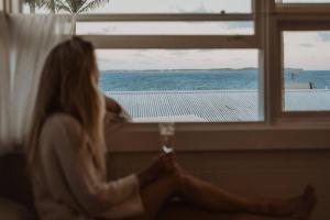 a woman sitting in a window looking out at the ocean at George @ Ethel & Odes in Bundeena