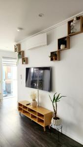 a living room with a tv on a white wall at Plush 3 bedroom property in Hobsonville in Auckland