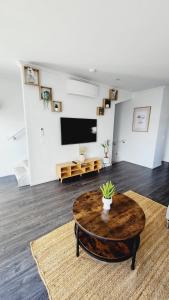 een woonkamer met een houten tafel en een televisie bij Plush 3 bedroom property in Hobsonville in Auckland
