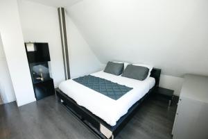 ein kleines Schlafzimmer mit einem Bett mit weißer Bettwäsche und grauen Kissen in der Unterkunft Gîte La Maison de Ludivine avec Terrasse et Parking in Orbey