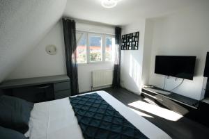 - une chambre avec un lit, une télévision et une fenêtre dans l'établissement Gîte La Maison de Ludivine avec Terrasse et Parking, à Orbey