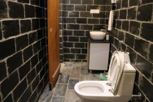 uma casa de banho com um WC branco numa parede de tijolos em Hobbit House Bir em Bir