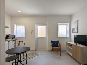 a living room with a table and a kitchen with a television at Canary's Suite in Matosinhos