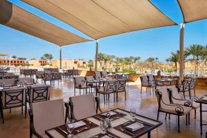 ein Restaurant mit Tischen und Stühlen und Blick auf die Wüste in der Unterkunft Jaz Grand Marsa in Bucht von Coraya