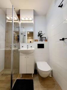La salle de bains blanche est pourvue de toilettes et d'un lavabo. dans l'établissement MiaApart National Stadium, MIĘDZYNARODOWA, à Varsovie