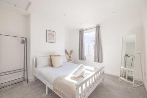 a white bedroom with a bed and a mirror at Cosy Cottage: Your Central Windsor Retreat in Windsor