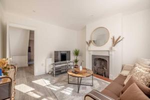 a living room with a couch and a table and a mirror at Cosy Cottage: Your Central Windsor Retreat in Windsor