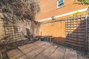 a brick wall with a bench next to a building at Cosy Cottage: Your Central Windsor Retreat in Windsor