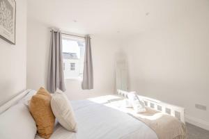 a bedroom with a white bed with pillows and a window at Cosy Cottage: Your Central Windsor Retreat in Windsor +1 photo