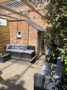 a patio with a couch on a wooden deck at Duck terrace in Kibworth Harcourt