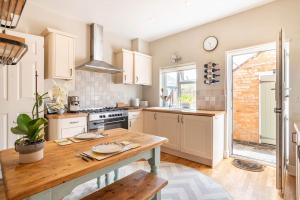 a kitchen with white cabinets and a wooden table at Duck terrace in Kibworth Harcourt