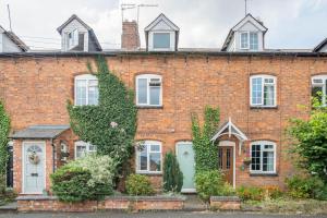 uma casa de tijolos vermelhos com uma porta verde em Duck terrace em Kibworth Harcourt