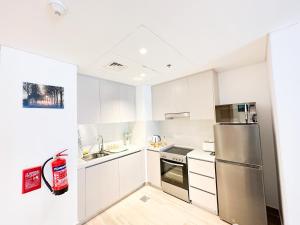 a kitchen with white cabinets and a stainless steel refrigerator at Bord de l'eau 214WB8 in Abu Dhabi