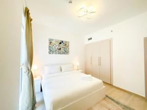 a white bedroom with a bed and a window at Bord de l'eau 214WB8 in Abu Dhabi
