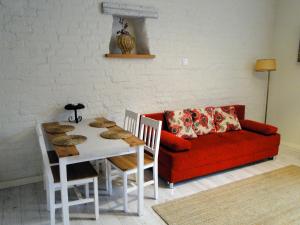 オルシュティンにあるKawalerka w centrum Starego Miastaのリビングルーム(赤いソファ、テーブル付)