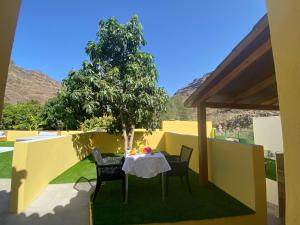 a table and chairs on a patio with a tree at SUNNY CARMELITO DELUXE in Mogán