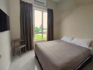 a bedroom with a bed and a window and a chair at Lembah Saerah Resort in Kangar