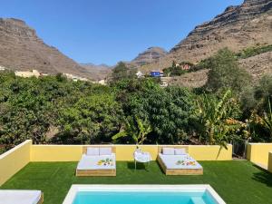 a resort with a pool and two beds and mountains at SUNNY CARMELITO DELUXE in Mogán