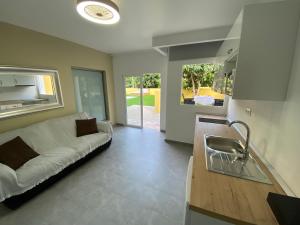 a living room with a white couch and a kitchen at SUNNY CARMELITO DELUXE in Mogán