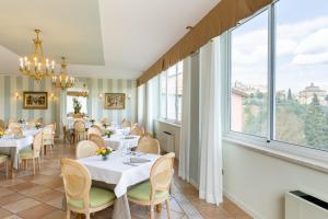 ein Restaurant mit Tischen und Stühlen und großen Fenstern in der Unterkunft Hotel Tuder in Todi