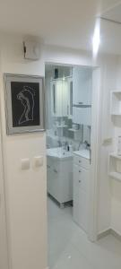 La salle de bains blanche est pourvue de comptoirs blancs et d'un lavabo. dans l'établissement Lamia, à Osijek