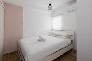 a white bedroom with a bed with white sheets and pillows at Central and beautiful - MORE apartments in Beer Sheva
