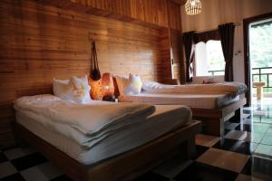 two beds in a room with wooden walls and a checkered floor at Ha Giang Historic House & tour in Ha Giang