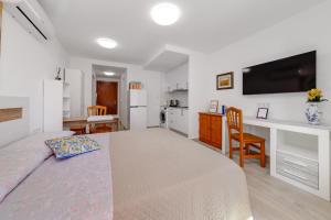 ein Schlafzimmer mit einem Bett und einem Schreibtisch sowie eine Küche in der Unterkunft Cosy Studio Playa del Cura in Torrevieja