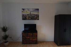Zimmer mit einem TV auf einer Kommode mit einem Bild an der Wand in der Unterkunft Ferienwohnung Hohenlimburg in Hagen