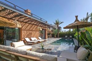 een patio met een zwembad, stoelen en een parasol bij Villa 4 chambres - Piscine in Marrakesh